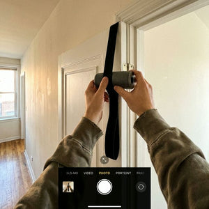 Hands placing foam-padded door anchor on white door