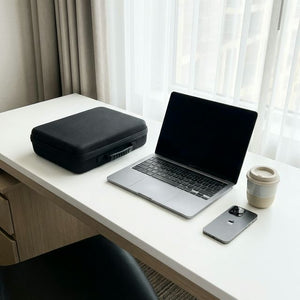 Matte black carry case next to laptop on hotel desk