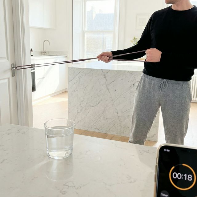 Person doing lateral band pull in bright kitchen