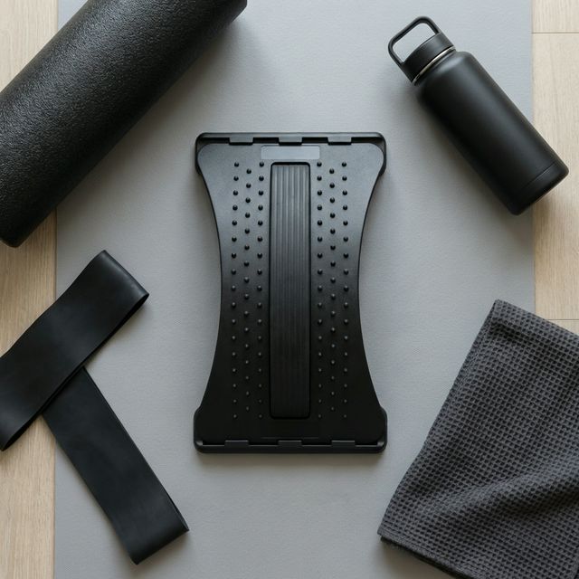 Flat-lay of back stretcher with foam roller, resistance band, and water bottle